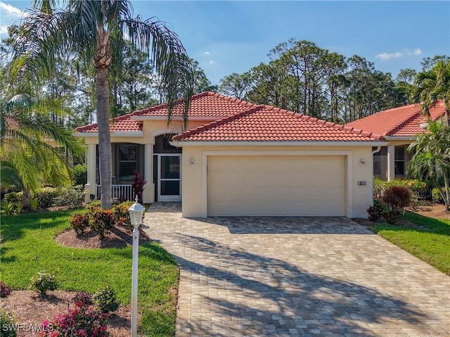 mediterranean / spanish home featuring a garage, a tiled roof, decorative driveway, and stucco siding