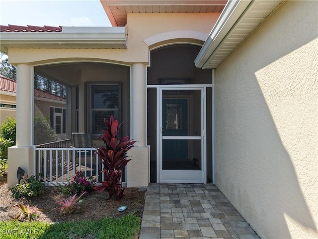 property entrance with a porch and stucco siding