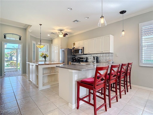 kitchen with a peninsula, a wealth of natural light, appliances with stainless steel finishes, and backsplash