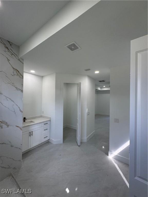 bathroom featuring visible vents, marble finish floor, vanity, stone wall, and recessed lighting