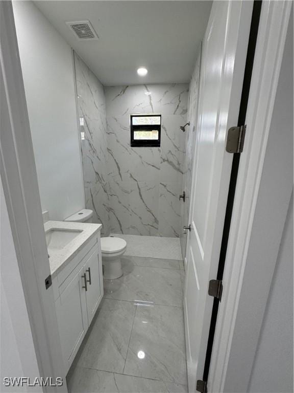 bathroom featuring marble finish floor, a marble finish shower, visible vents, toilet, and vanity