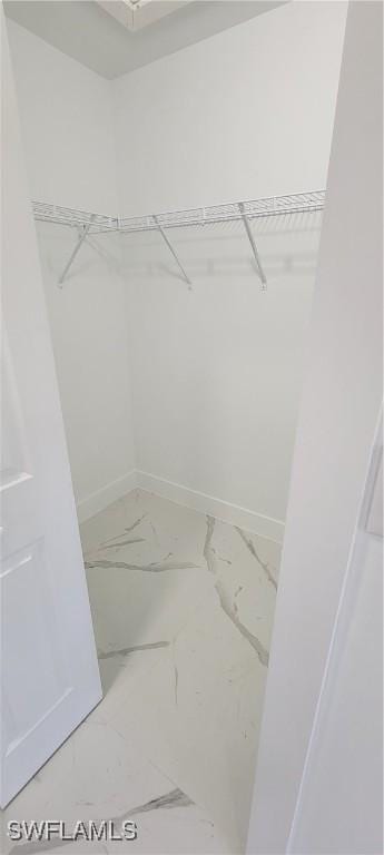 walk in closet with marble finish floor