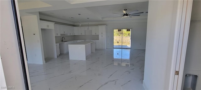 1025 Pilgrim St E, Lehigh Acres, FL 33974 - kitchen with ceiling fan, a kitchen island, white cabinetry, light marble finish floors, and a sink