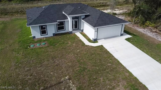 1025 Pilgrim St E, Lehigh Acres, FL 33974 - view of front of house with a shingled roof, concrete driveway, a garage, stucco siding, and a front lawn