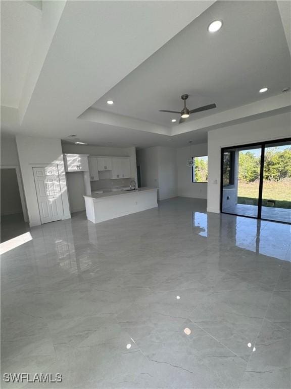 unfurnished living room featuring ceiling fan, recessed lighting, a sink, marble finish floor, and a raised ceiling