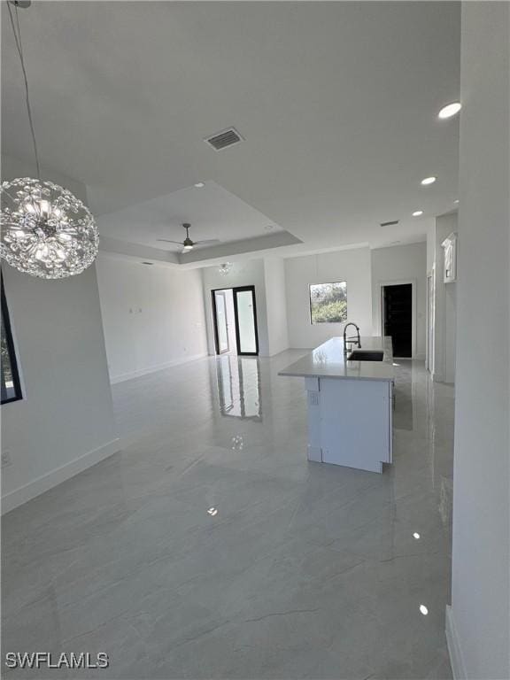 unfurnished room featuring a tray ceiling, marble finish floor, visible vents, ceiling fan, and baseboards