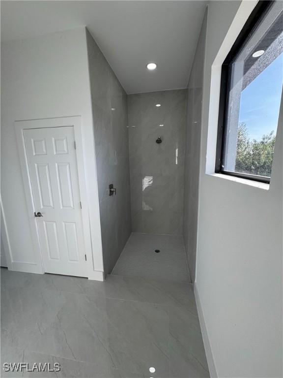 full bath featuring marble finish floor, baseboards, and a walk in shower