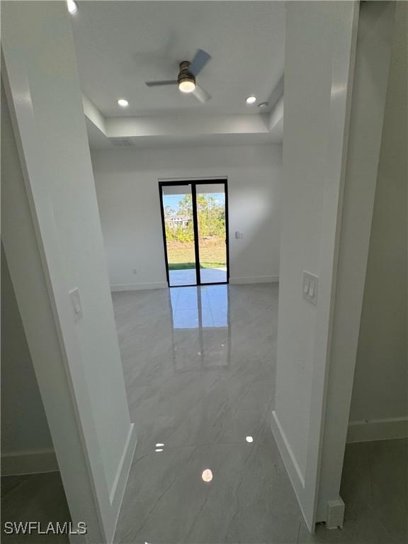 interior space featuring a raised ceiling and baseboards