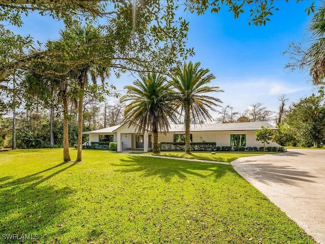 view of front of property with stucco siding, concrete driveway, and a front lawn