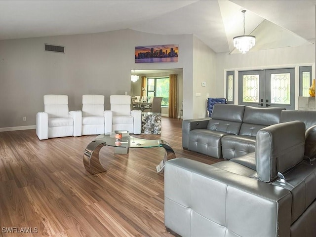 living area with visible vents, lofted ceiling, and wood finished floors