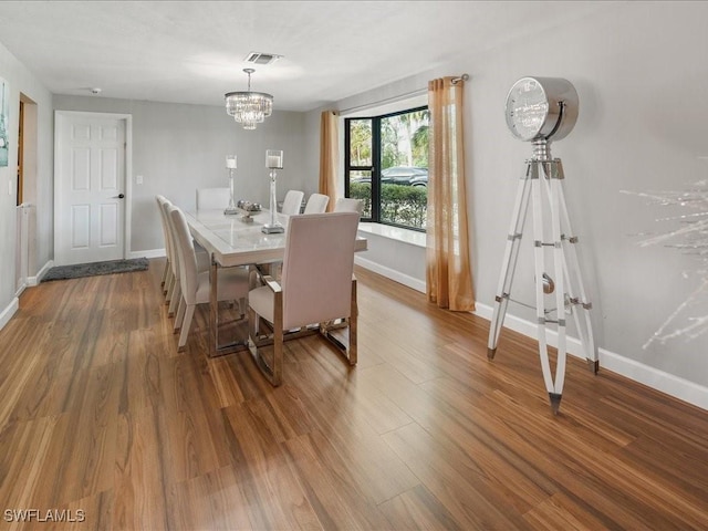 dining space featuring visible vents, baseboards, wood finished floors, and a chandelier