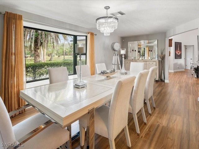 dining room featuring an inviting chandelier, light wood-style flooring, baseboards, and visible vents