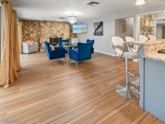 interior space featuring baseboards, visible vents, a stone fireplace, and light wood-style floors