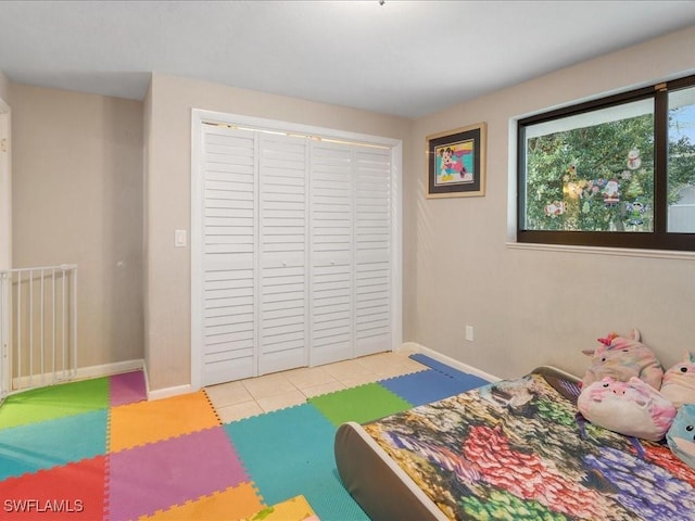 bedroom with a closet, light tile patterned floors, and baseboards