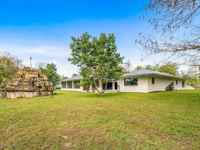 rear view of house with a yard, central AC, and a sunroom