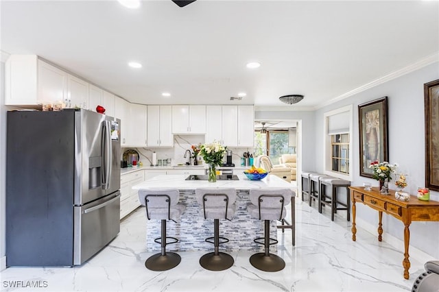 kitchen featuring stainless steel fridge, decorative backsplash, ornamental molding, a breakfast bar, and marble finish floor