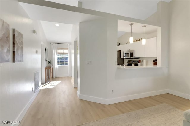 interior space featuring visible vents, vaulted ceiling, light wood-style flooring, and baseboards