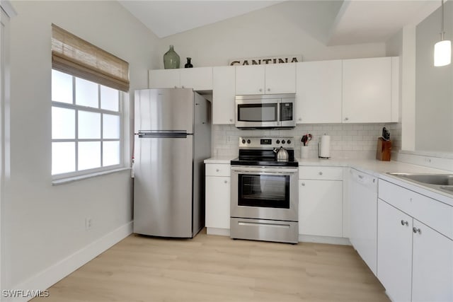 kitchen featuring light wood-style flooring, white cabinetry, light countertops, appliances with stainless steel finishes, and backsplash