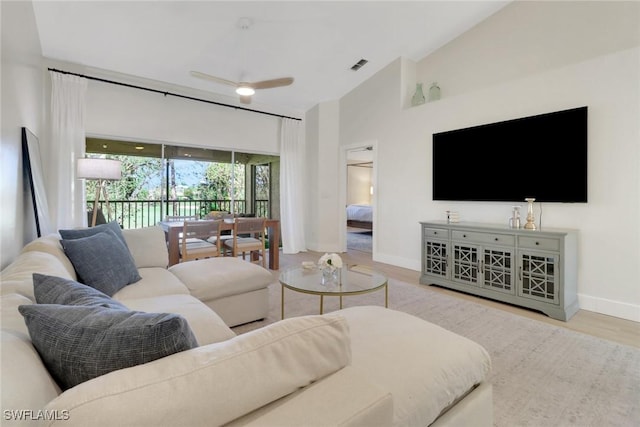 living area featuring ceiling fan, wood finished floors, visible vents, baseboards, and vaulted ceiling