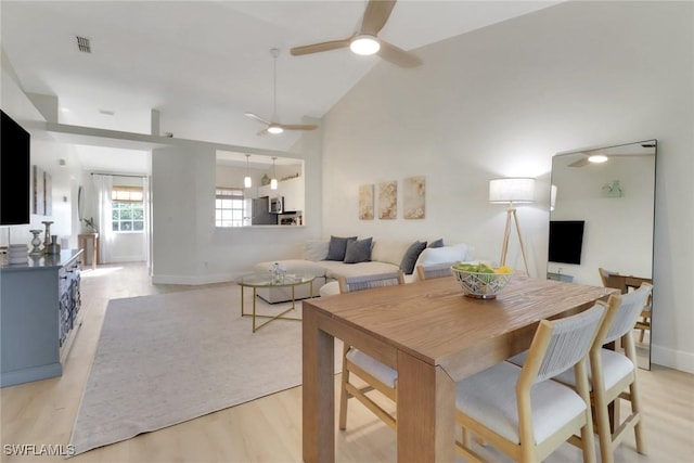 dining space with light wood-type flooring, high vaulted ceiling, visible vents, and a ceiling fan