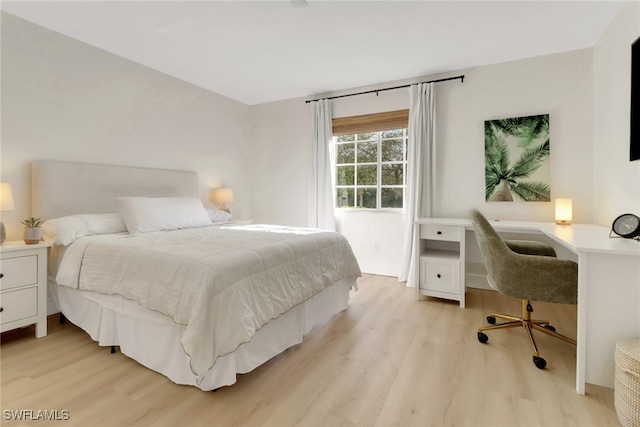 bedroom with built in desk and light wood-type flooring