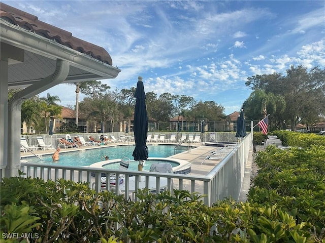 community pool with a jacuzzi, fence, and a patio