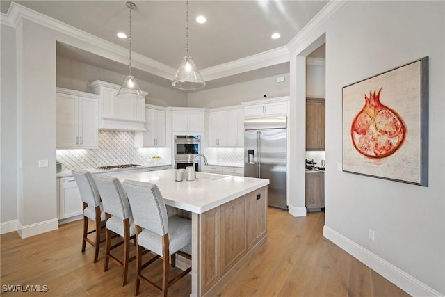 kitchen with a breakfast bar area, stainless steel appliances, a sink, light wood-style floors, and light countertops