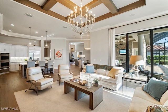 living area with visible vents, beam ceiling, coffered ceiling, an inviting chandelier, and light wood finished floors