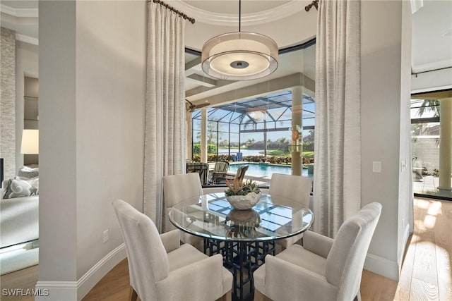 dining area featuring wood finished floors, a water view, baseboards, and a sunroom
