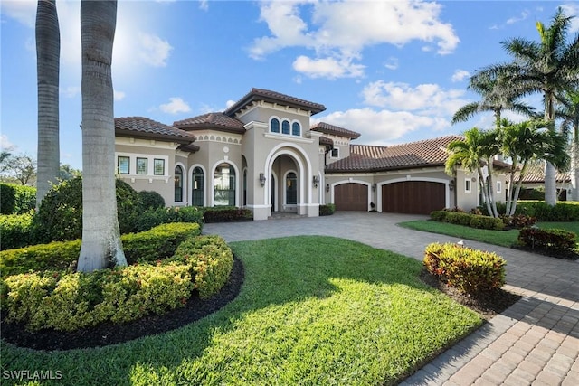 mediterranean / spanish house with stucco siding, a front lawn, a garage, a tile roof, and decorative driveway