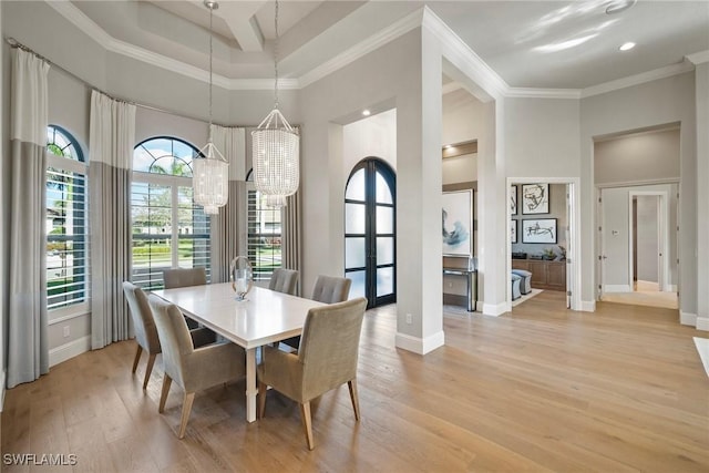 dining area featuring ornamental molding, a high ceiling, baseboards, and light wood finished floors