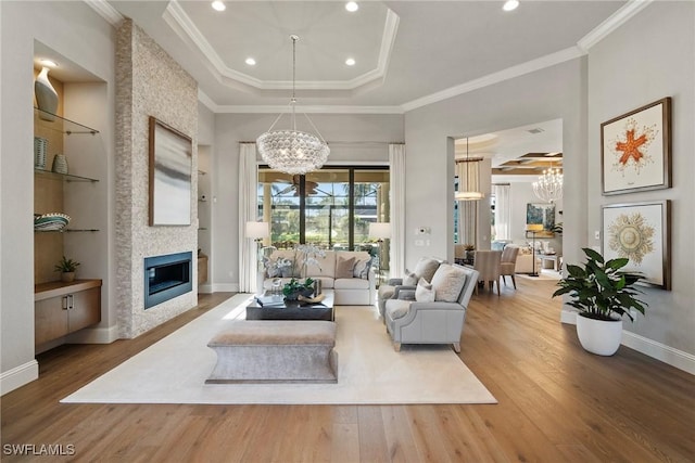 living area featuring wood finished floors, a fireplace, built in features, and a notable chandelier