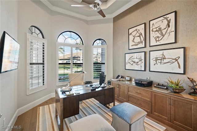 home office featuring crown molding, ceiling fan, baseboards, and light wood-style floors