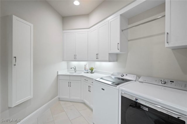 clothes washing area featuring light tile patterned floors, a sink, baseboards, cabinet space, and washing machine and clothes dryer