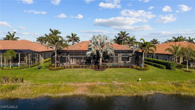 rear view of property with a lanai, a tiled roof, a lawn, and a water view