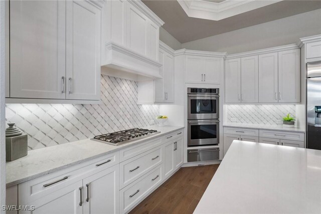 kitchen featuring premium range hood, white cabinetry, appliances with stainless steel finishes, a warming drawer, and dark wood finished floors