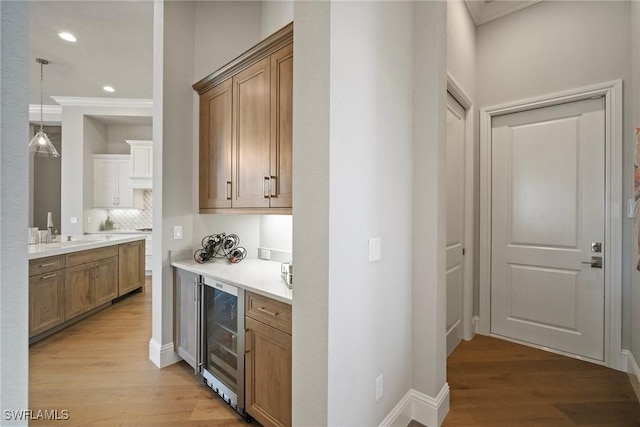 bar featuring recessed lighting, a sink, ornamental molding, wine cooler, and light wood-type flooring