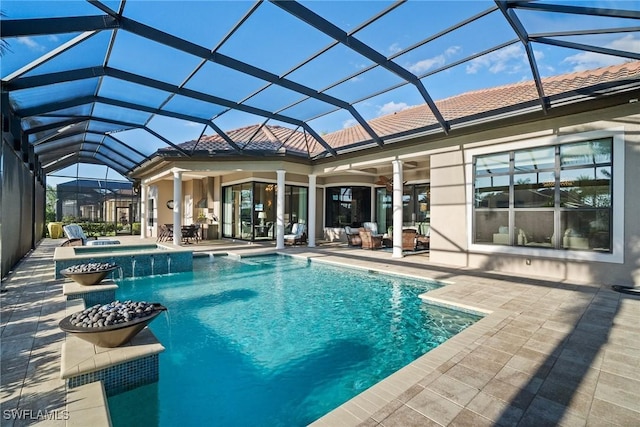 view of swimming pool with glass enclosure, a pool with connected hot tub, and a patio area
