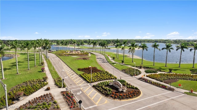 view of community with a lawn, a water view, and fence