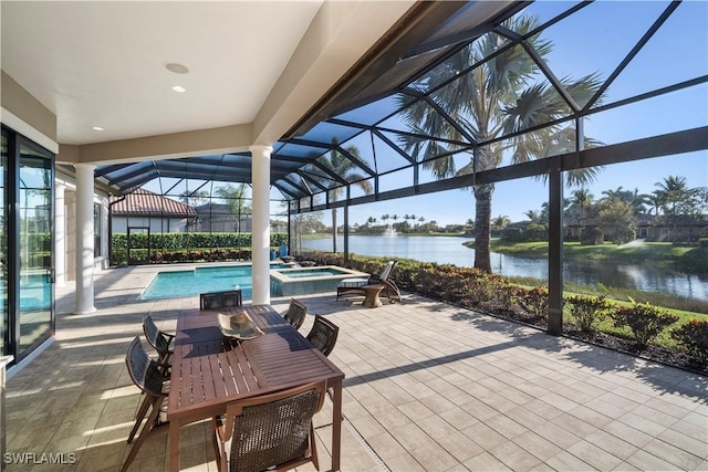 exterior space with glass enclosure, a water view, and a pool with connected hot tub