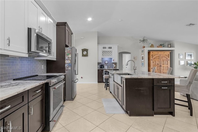 kitchen featuring white cabinets, appliances with stainless steel finishes, arched walkways, and light tile patterned flooring