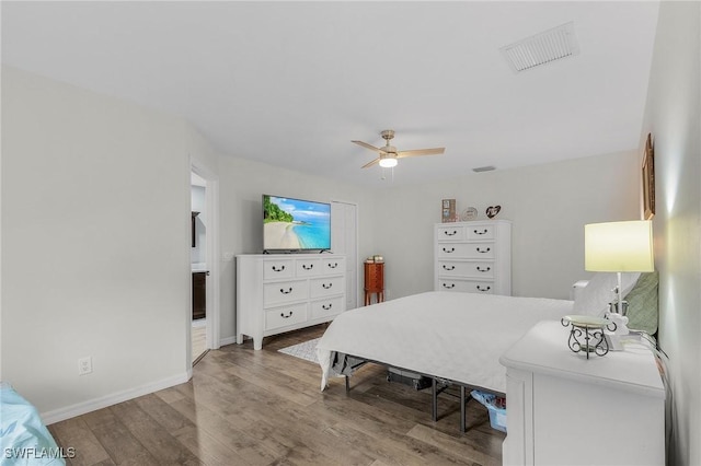 bedroom featuring visible vents, ceiling fan, baseboards, and wood finished floors