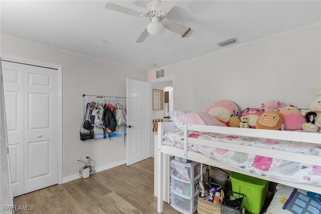 bedroom with baseboards, visible vents, ceiling fan, wood finished floors, and a closet