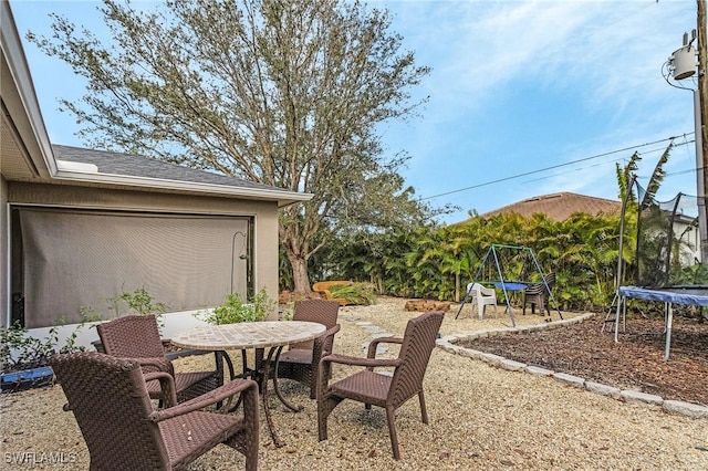 view of patio with a trampoline and outdoor dining space