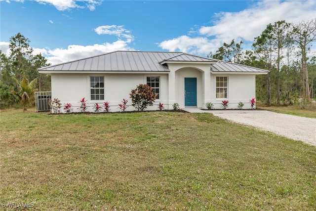 single story home featuring a standing seam roof, metal roof, a front lawn, and stucco siding