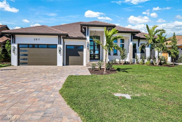 view of front of home with a front lawn, decorative driveway, a garage, and stucco siding