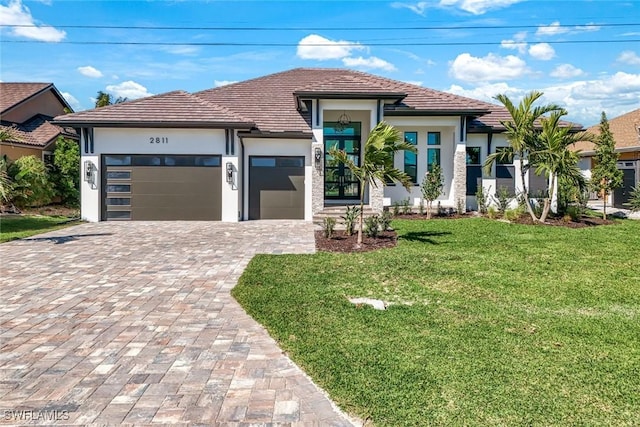 view of front of home with a front yard, stucco siding, a garage, a tile roof, and decorative driveway