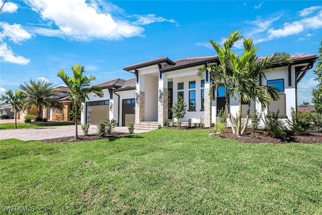 view of front of house with stucco siding, an attached garage, decorative driveway, and a front yard