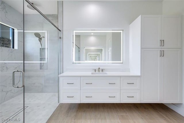 bathroom featuring vanity, wood finished floors, and a marble finish shower