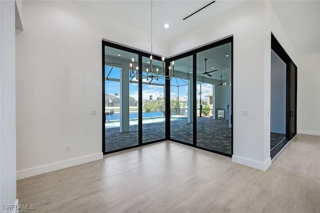 spare room with recessed lighting, an inviting chandelier, baseboards, and wood finished floors